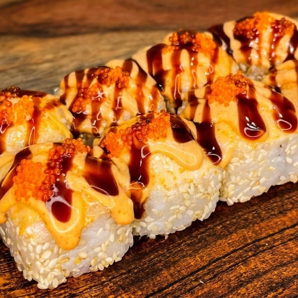 Eight sushi rolls with sesame seeds, drizzled with orange sauce, dark glaze, and orange tobiko.