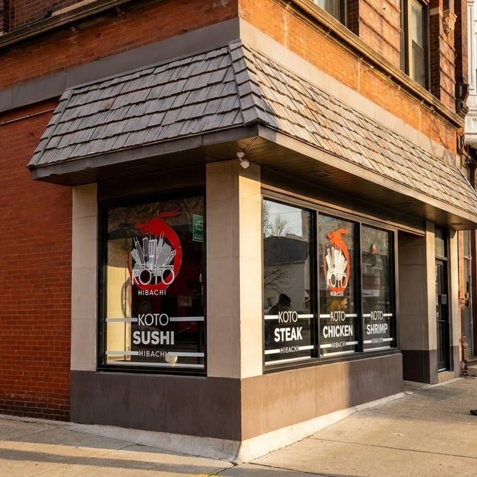 Exterior of Koto Hibachi restaurant on a street corner with a person walking by.